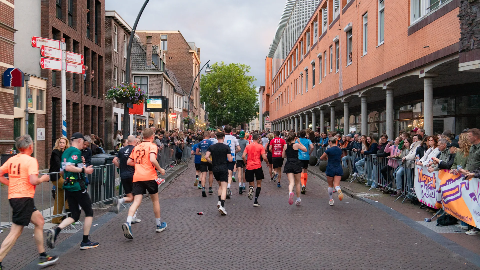 Lopers worden door een volle Zwolse straat aangemoedigd