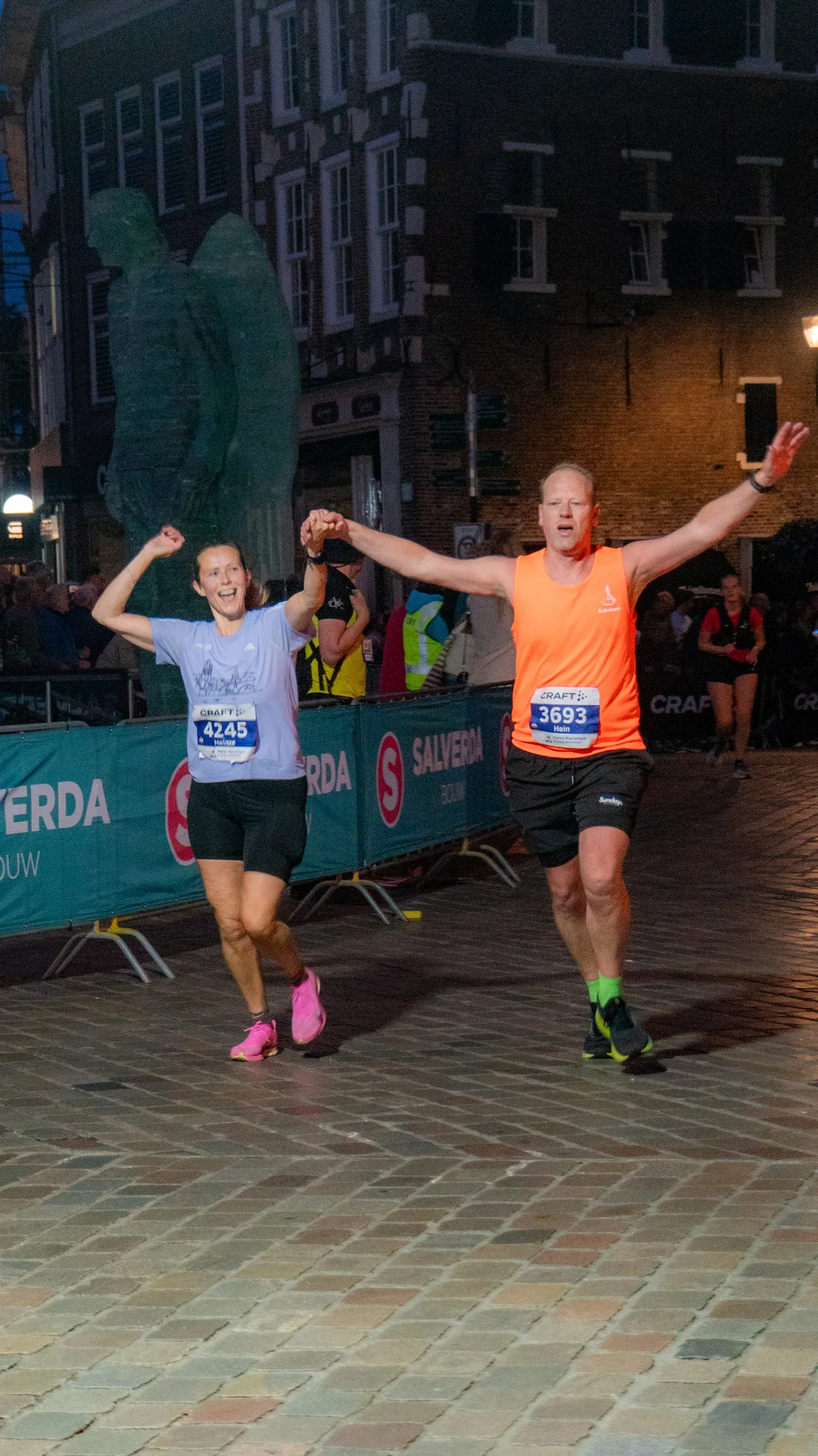Twee lopers komen hand in hand en lachend over de finish