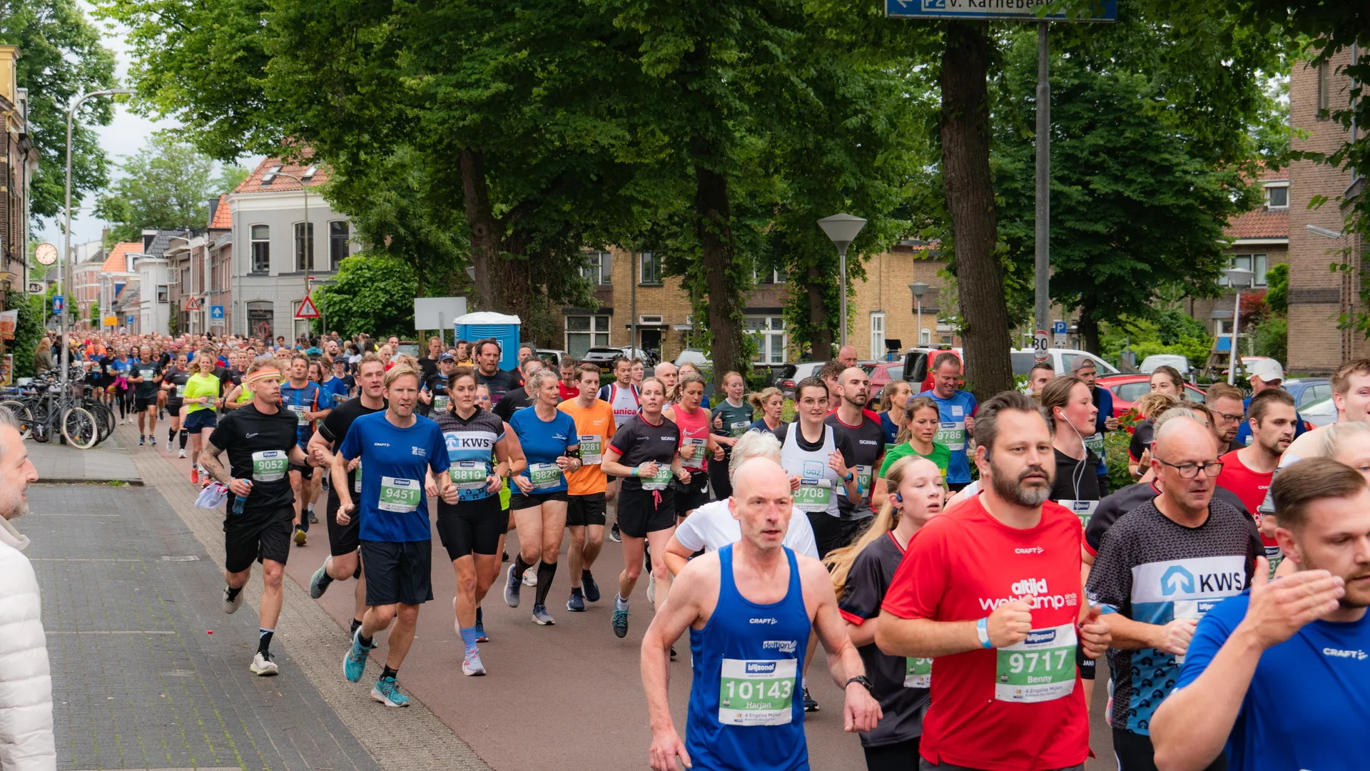 Een groot peloton lopers trekt door een groene straat in Zwolle