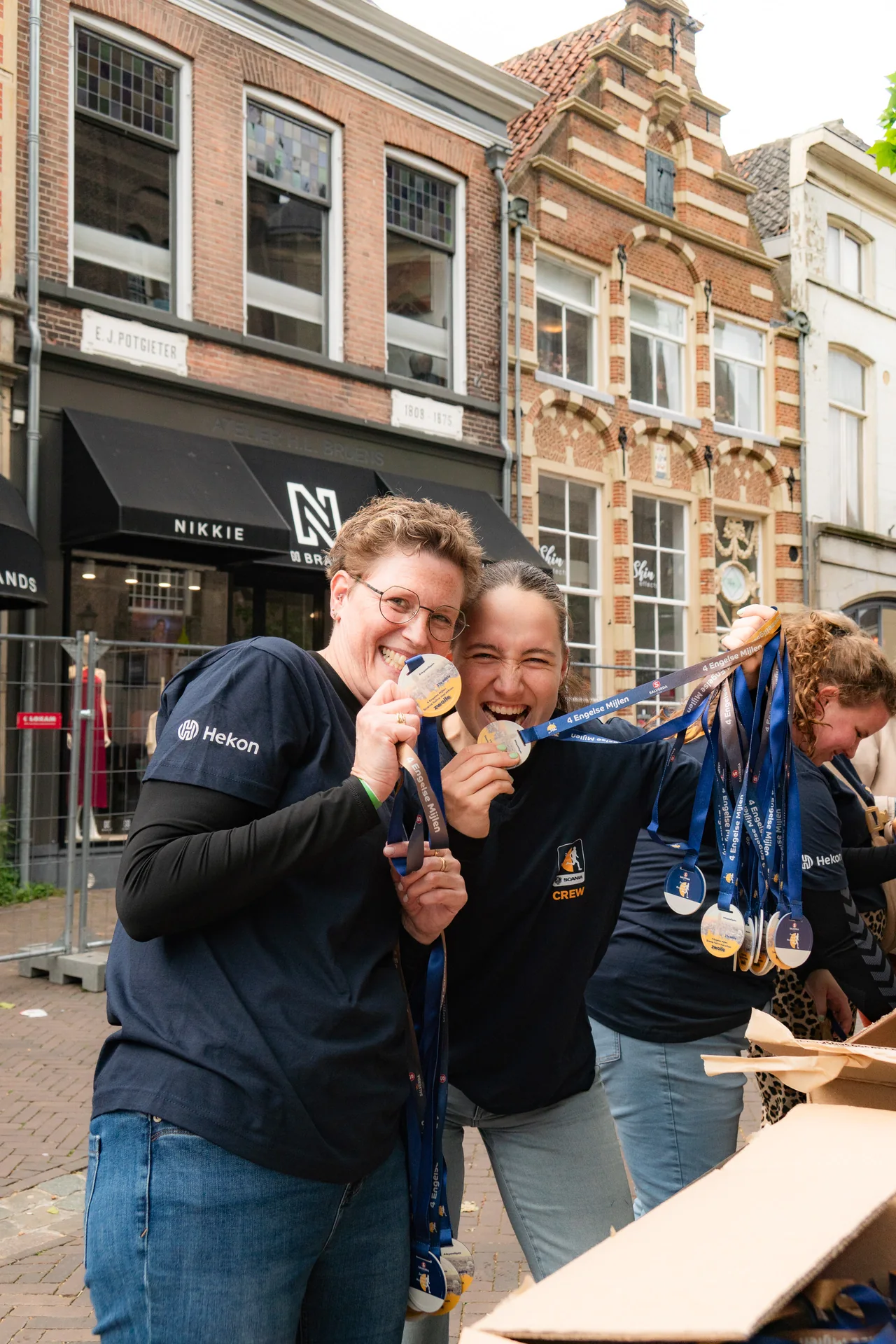 Twee vrijwilligers tonen trots de medailles van de Halve Marathon Zwolle
